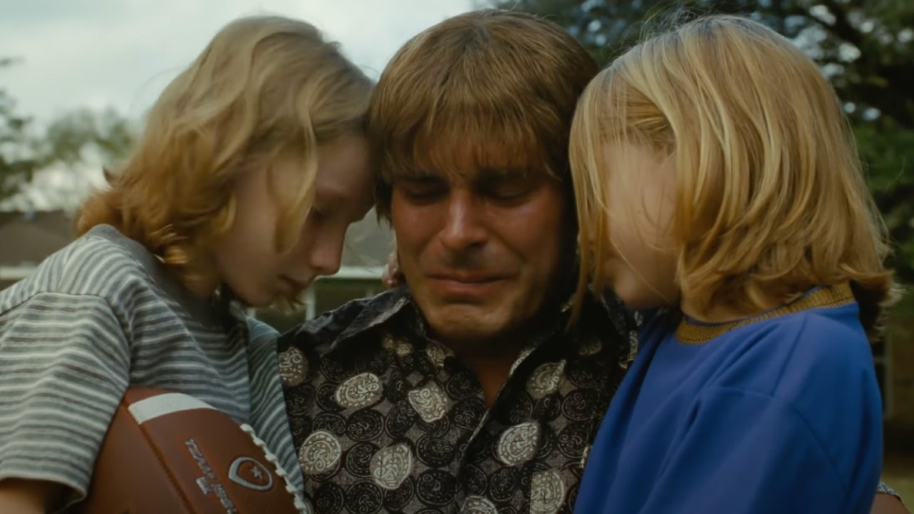 Kevin Von Erich llorando y sosteniendo a sus dos hijos