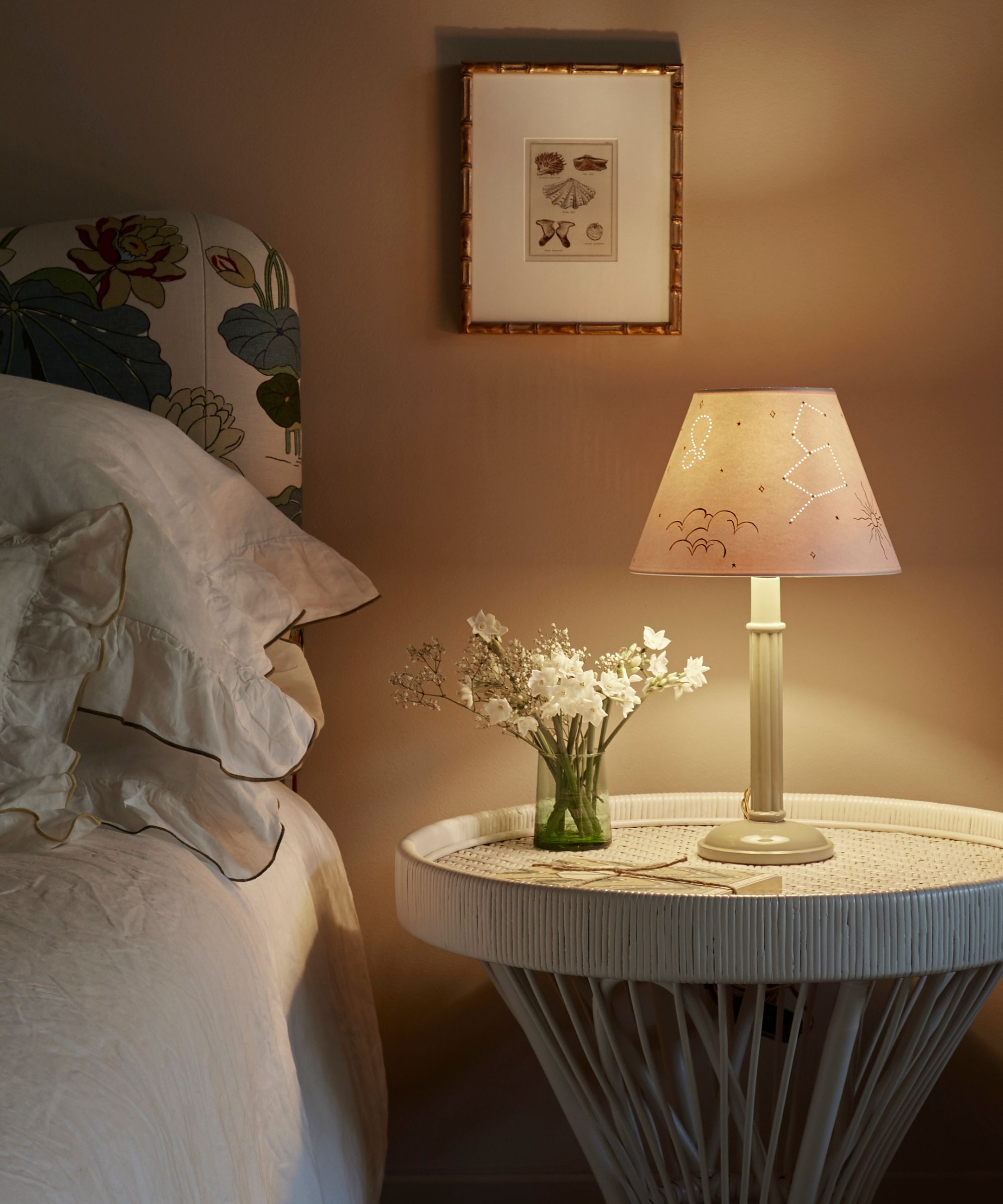 bedroom with neutral walls and a statement floral headboard with a soft bedside lamp glowing
