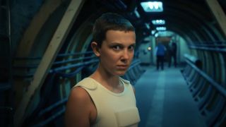 Millie Bobby Brown stands near a secret lab entrance in Stranger Things 4.