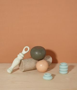Neutral peach background and base, stone circular block, with a peach and a brown round ornament, sex toys in shot