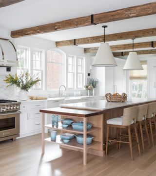 Bright kitchen with large wooden island and marble worktop, ceiling beams