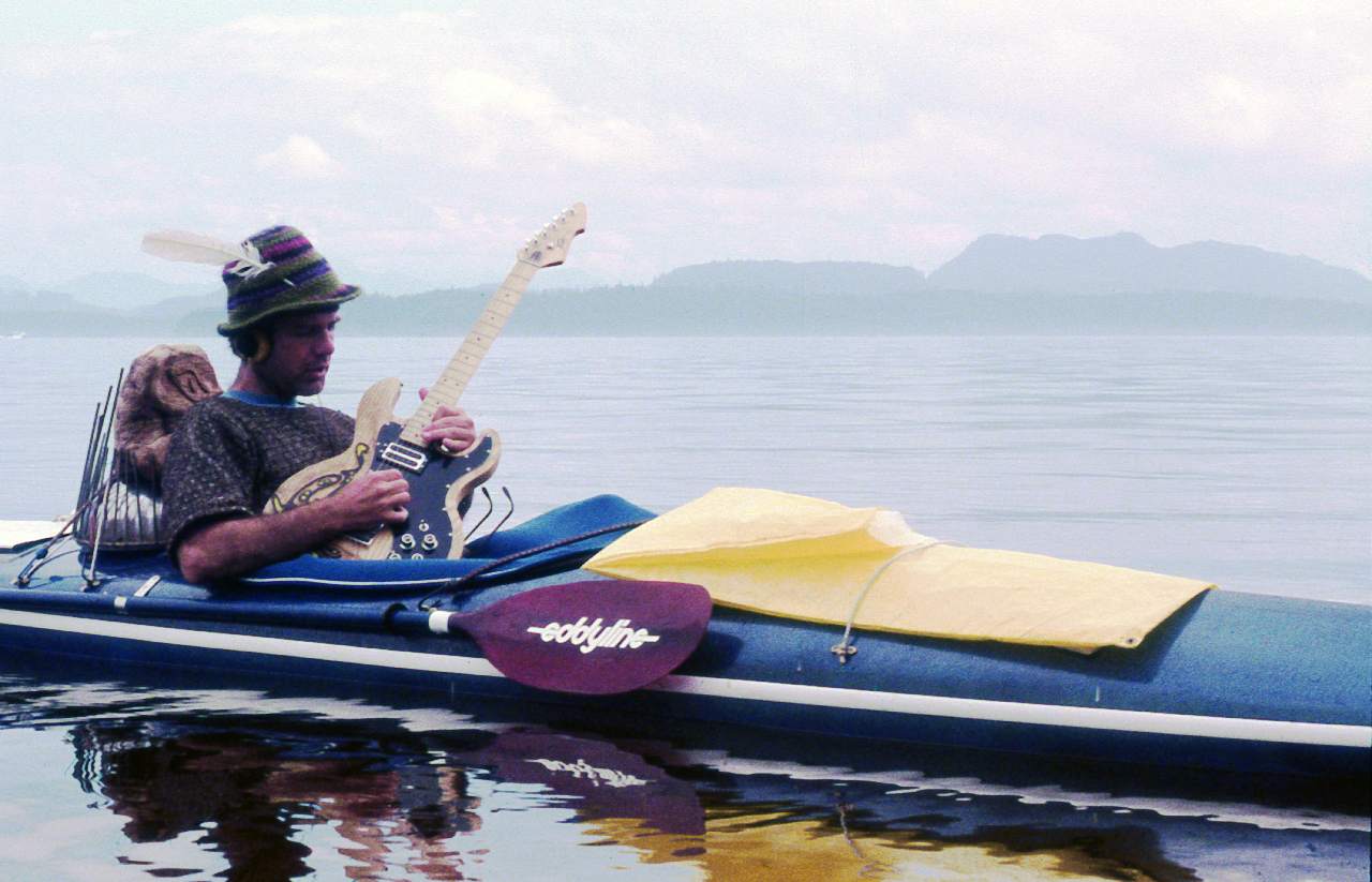 JIm Nollman playing guitar in a kayak
