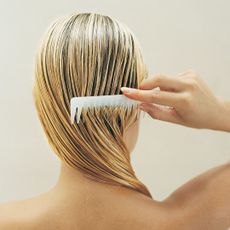 Blonde woman running a comb through wet hair
