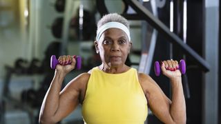 Woman doing overhead press with dumbbells in a gym