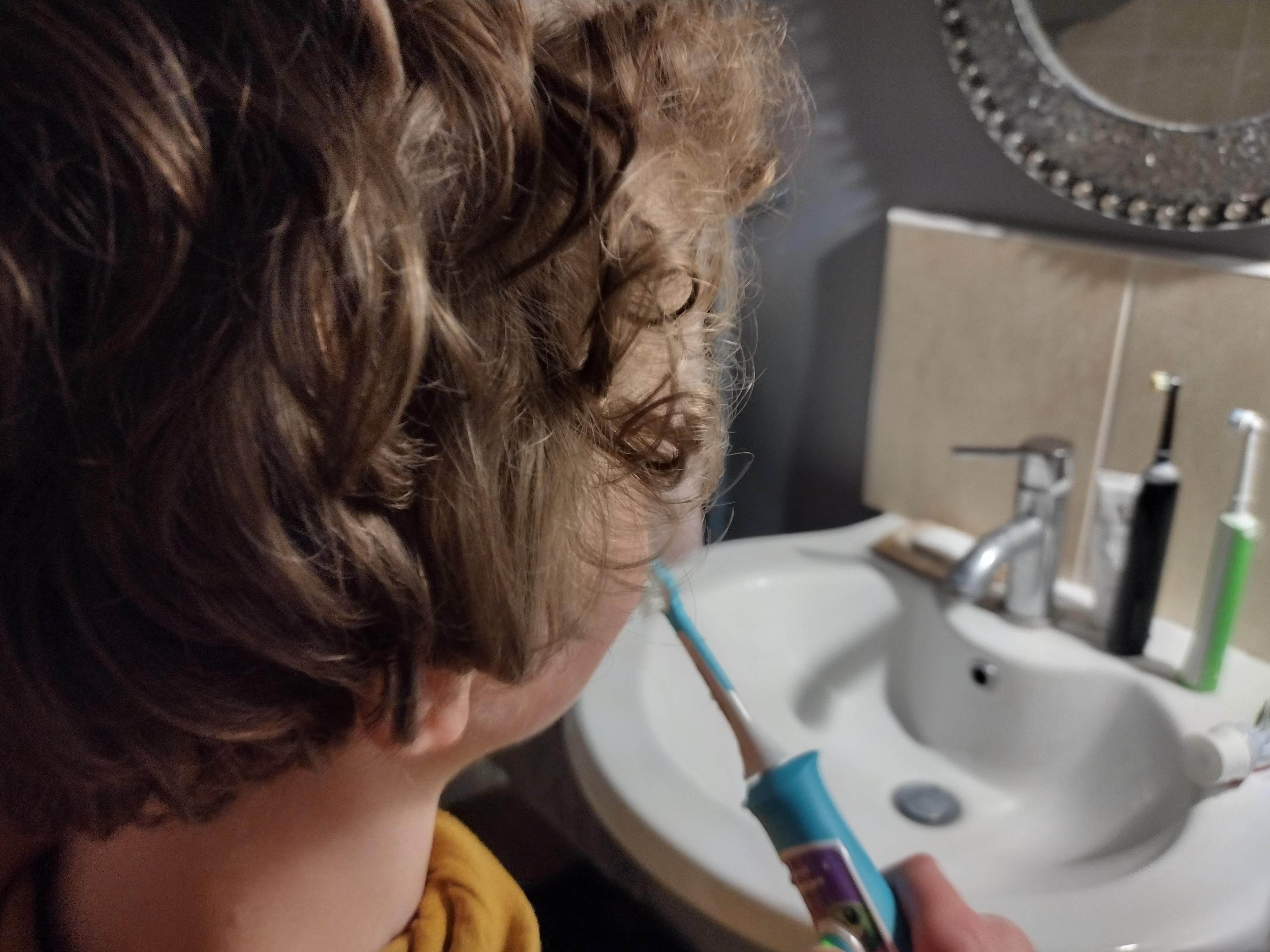young boy using the philips sonicare for kids electric toothrbush