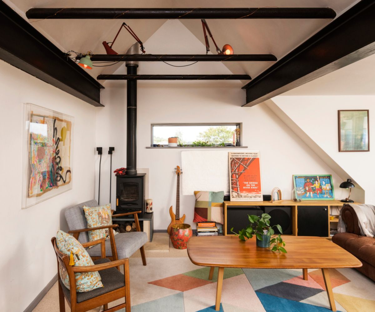 interior living space of eco home with black beams and log burner in corner of room