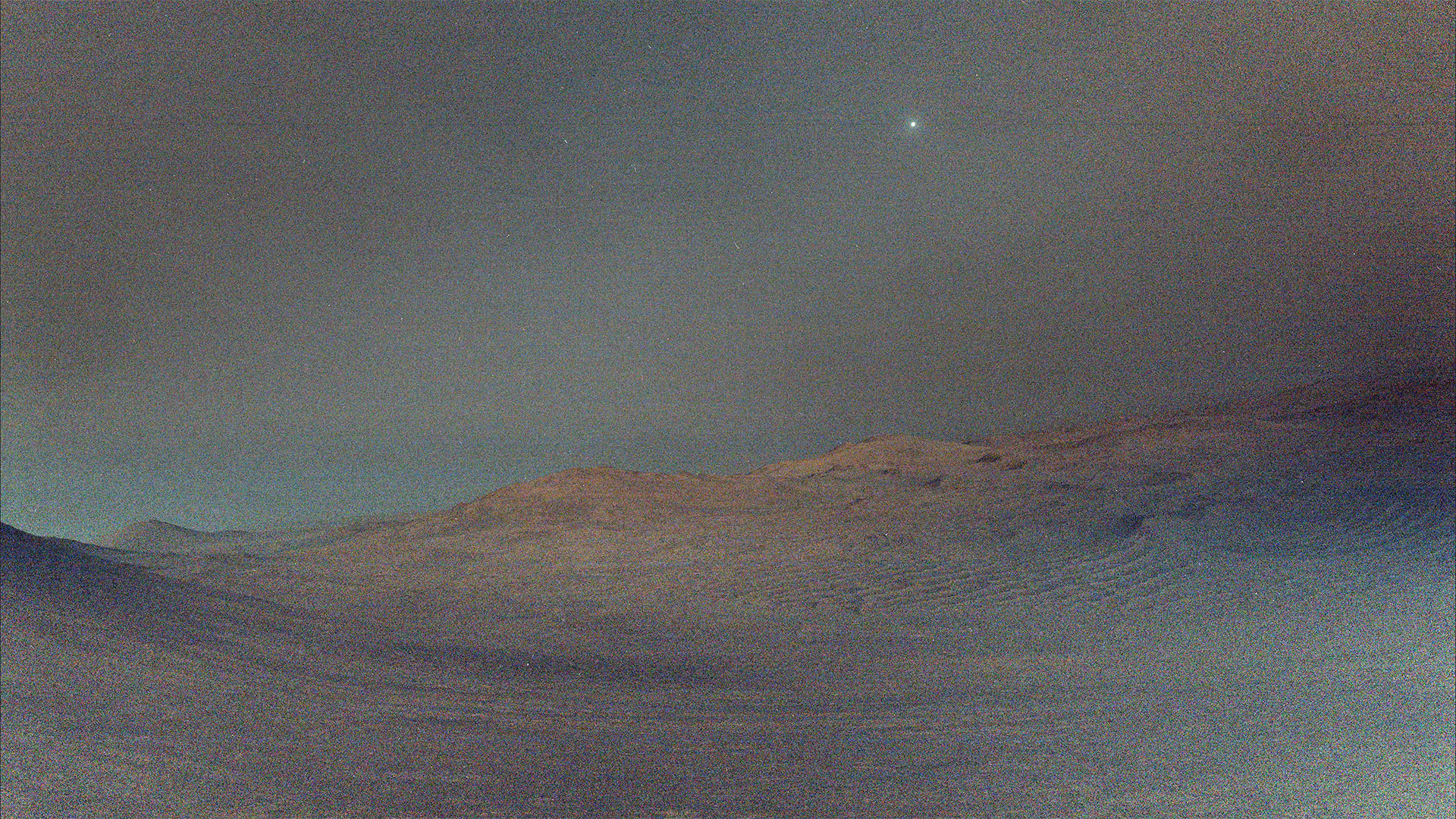 a star-like pinpoint of light hangs in the sky above a dimly light red-tinted surface