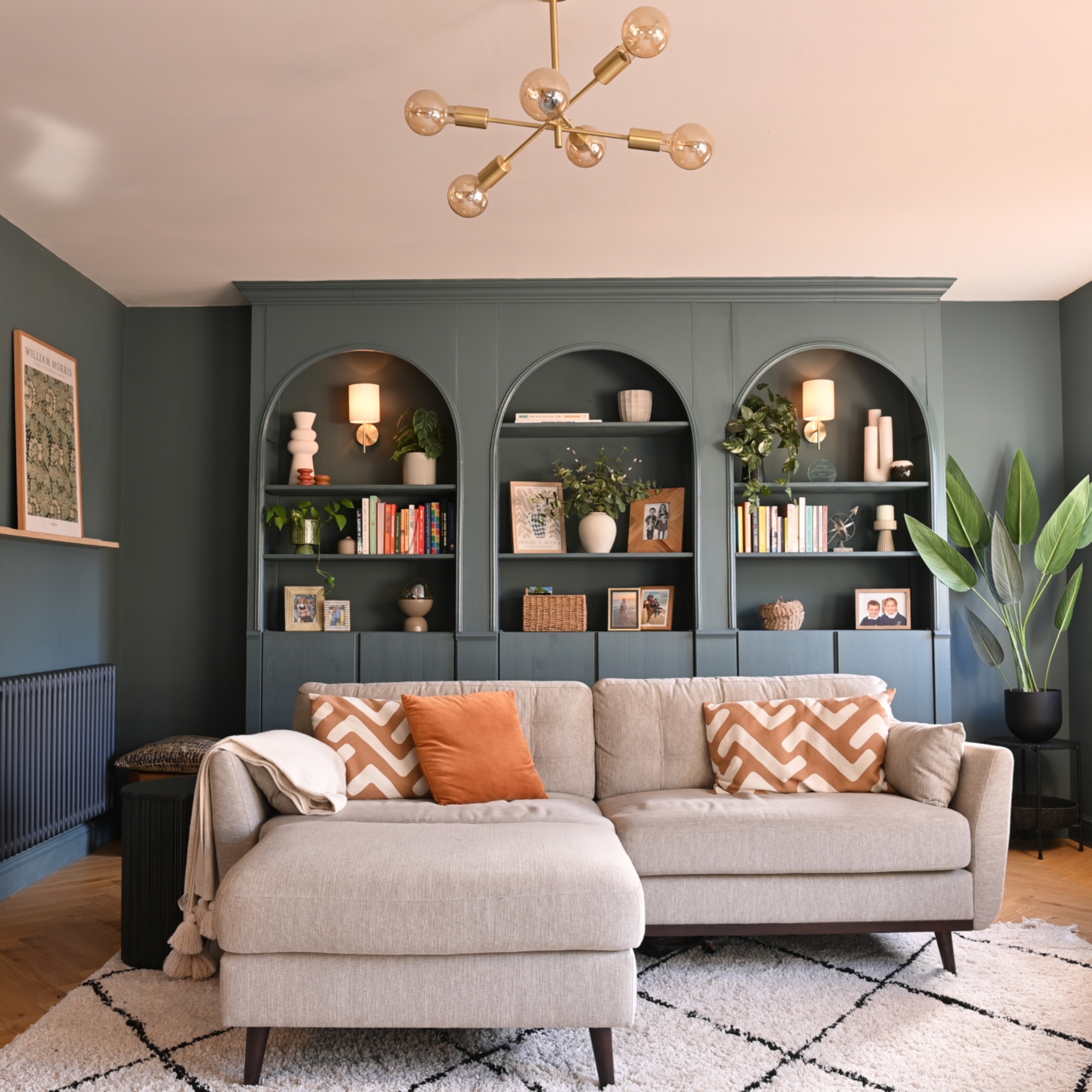 blue living room with beige L shaped sofa, bespoke shelving, rug