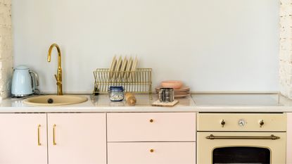 A small kitchen with pink cupboards