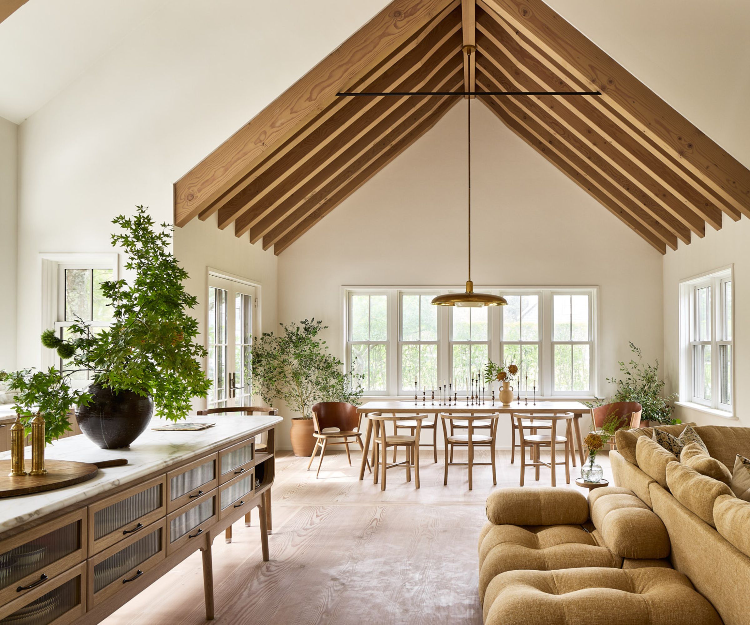 An open-plan kitchen/living/dining area with wooden cabinets and earth-toned decor