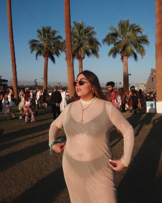 The Coachella influencer wears a dazzling sheer dress with a black bra, black underwear and round sunglasses.