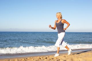 An older woman runs on a beach