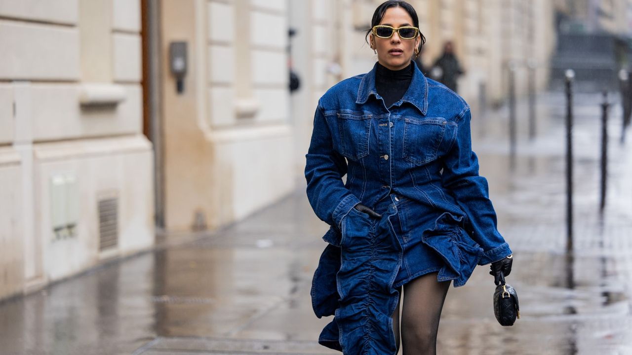 A woman in a denim jacket and mini skirt GettyImages-1940051151