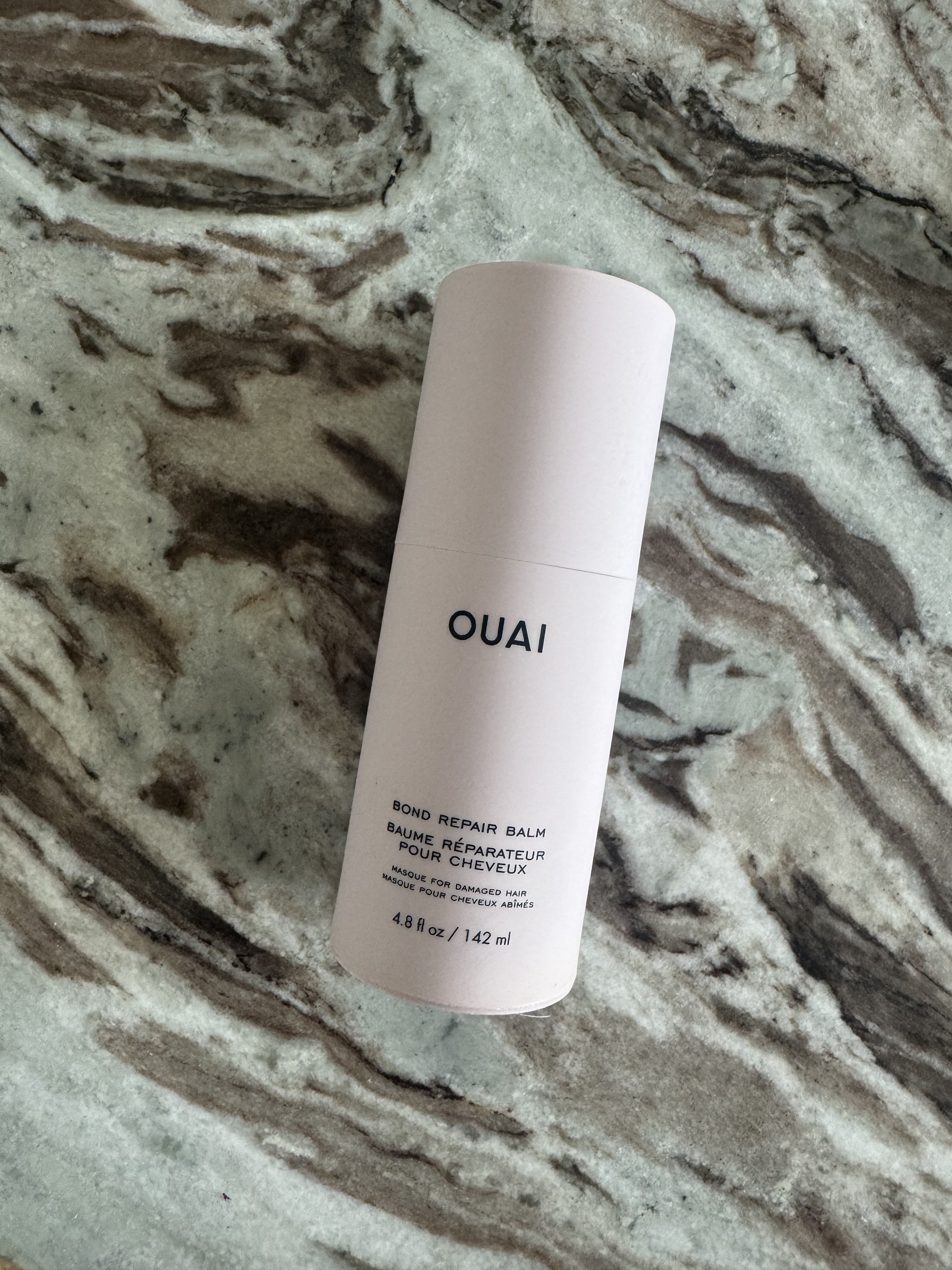 The Ouai Bond Repair Balm bottle on a marble table
