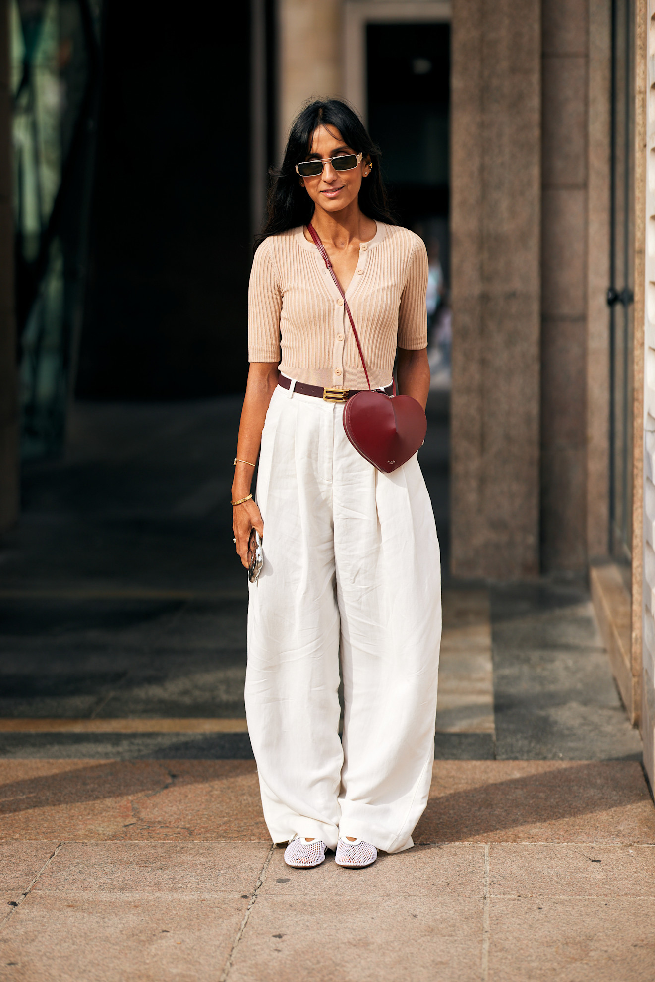 a milan spring 2025 fashion week attendee wearing a henley knitted shirt and white linen pants