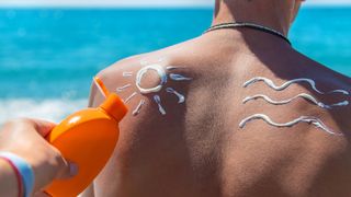 Sunscreen being applied to a man's back