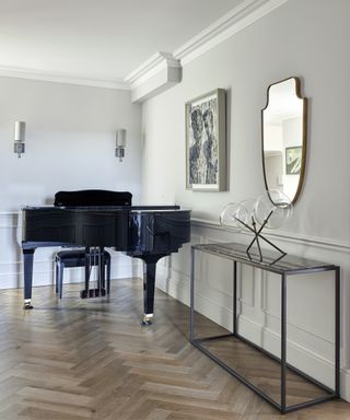 A modern hallway idea with grey walls, black console table and black grand piano