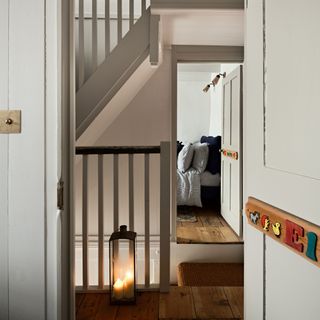 Open door looking into bedroom across hallway lit by lamp