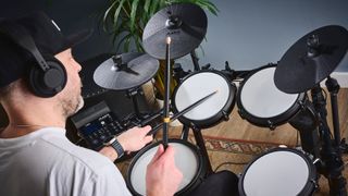 Man plays Alesis Nitro Max drum kit with black sticks