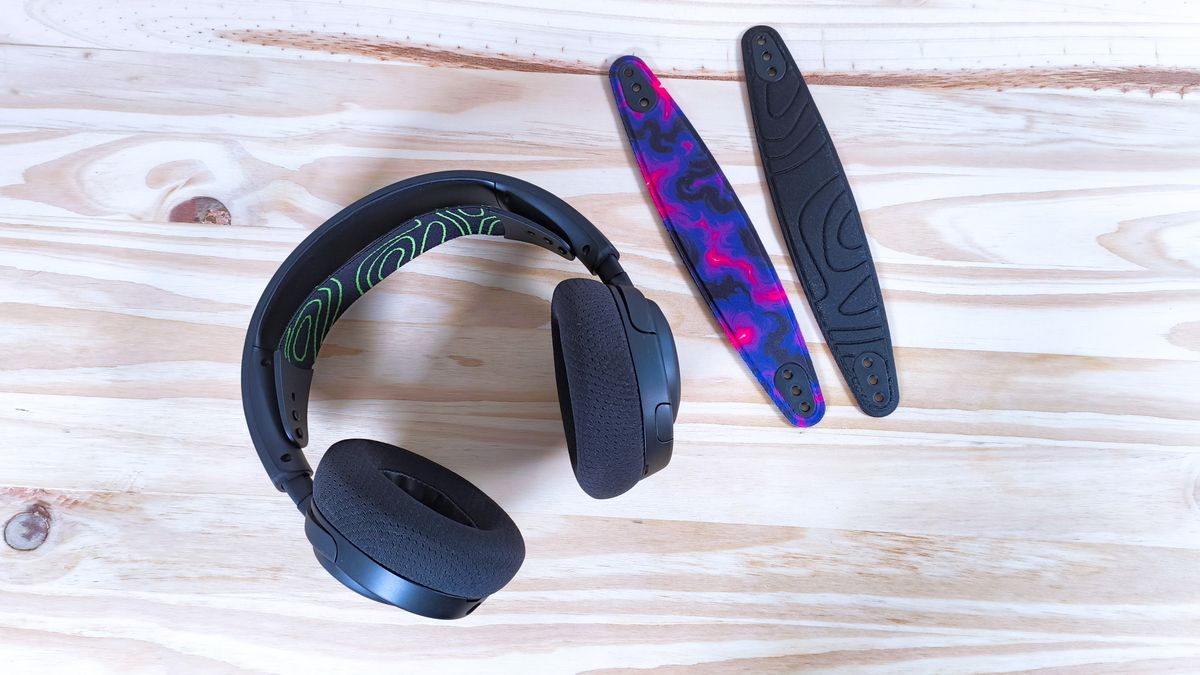 The SteelSeries Arctis Nova 5X in black on a wood table next to two extra suspension headbands