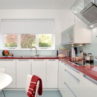 white kitchen with red worktop and cabinet