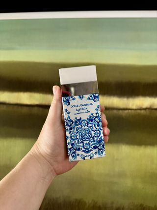 A bottle of Dolce & Gabbana Light Blue Summer Vibes on a blue and green background.