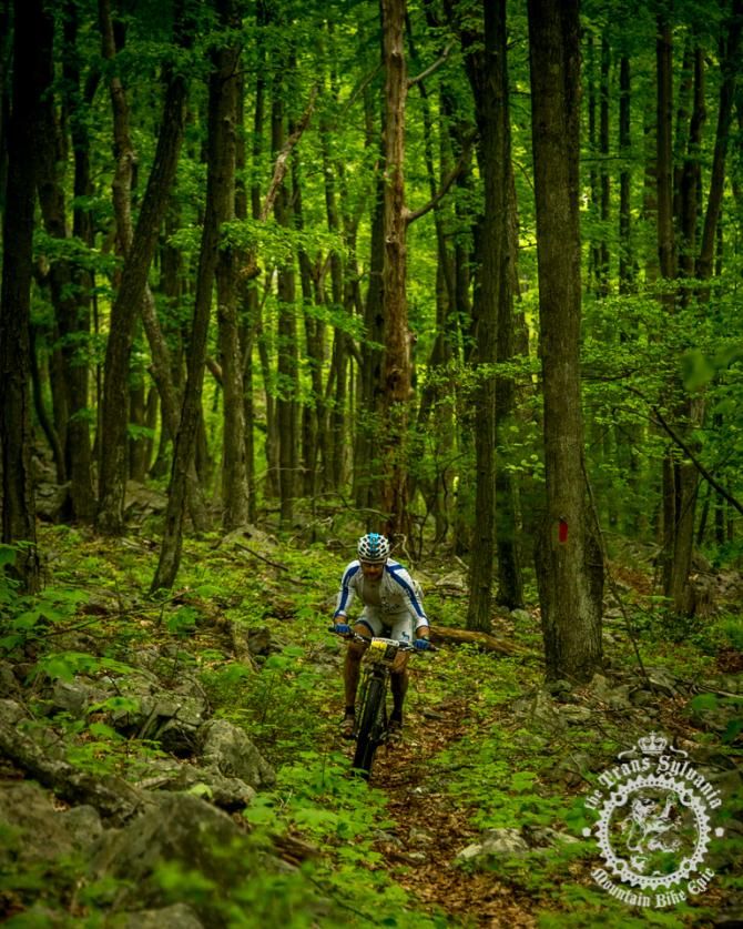 Mike Hebe rides through the green background under the precipitation of Stage 5