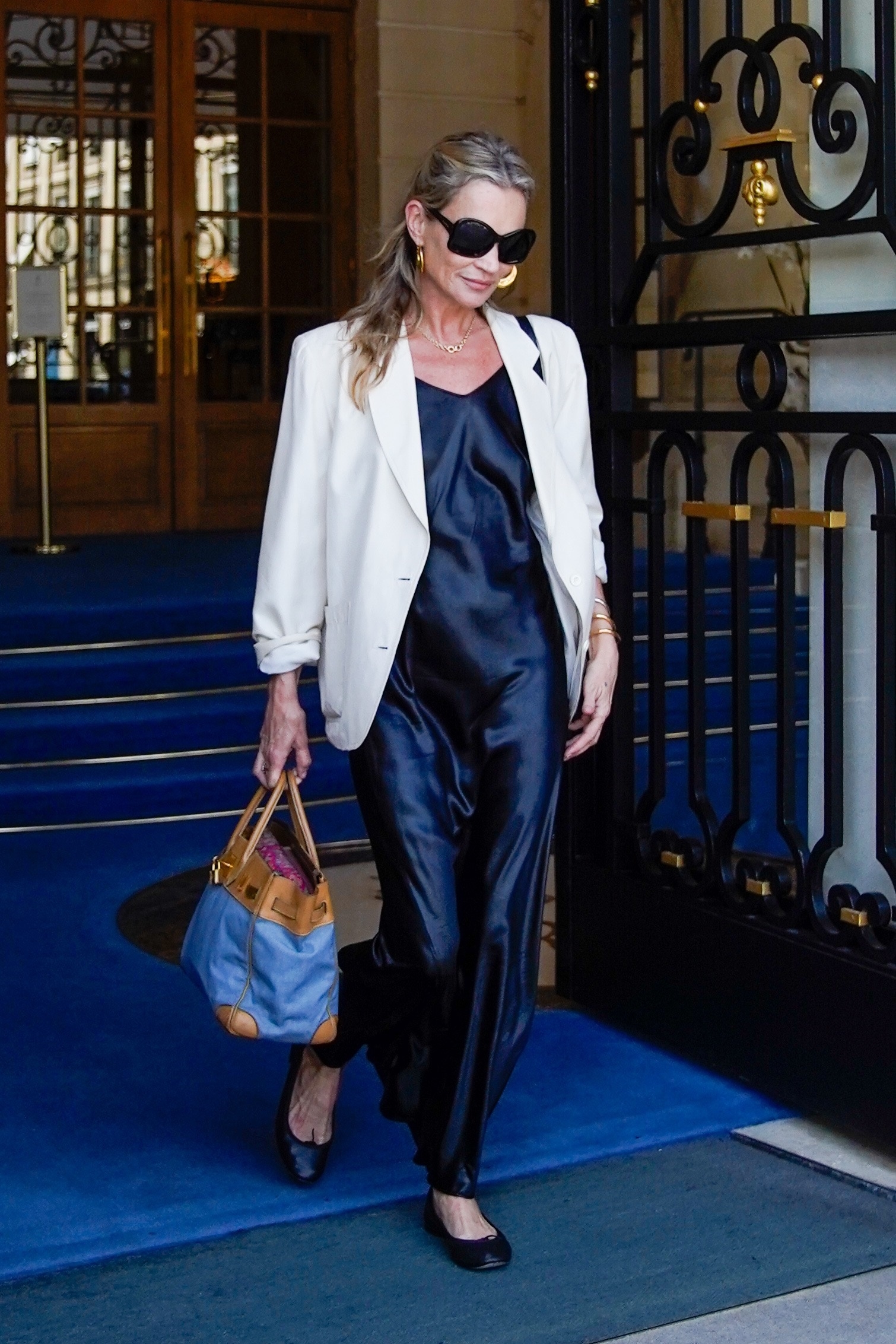 An image of Kate Moss wearing a silk dress with a white blazer and ballet flats whilst in Paris in 2026.