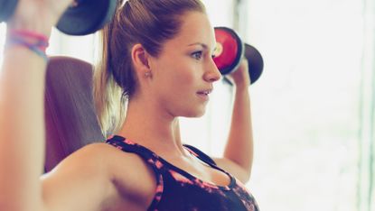 Woman performs a shoulder dumbbell press