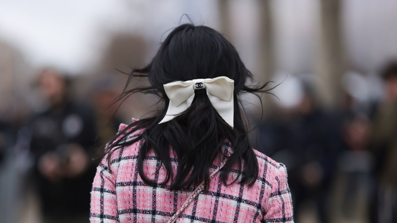 Susanna Lau seen wearing a pink tweed jacket with matching mini skirt, light blue cardigan, pink decorated Chanel bag, white tights, light blue high Chanel boots, outside Chanel Show, during the Womenswear Fall/Winter 2024/2025 as part of Paris Fashion Week on March 05, 2024 in Paris, France