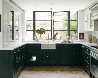 Forest green kitchen in U-shaped configuration with ceramic sink, parquet wooden flooring and crittall style windows