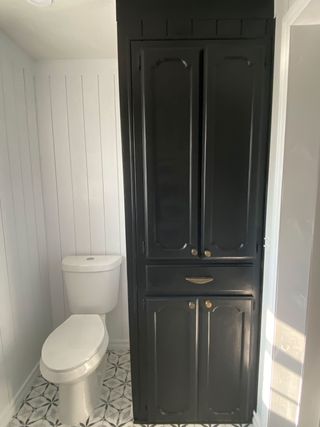 White guest bathroom with wall paneling and matching black rim mirrors