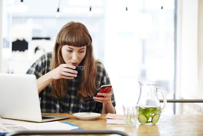 Woman drinking coffee and using a smartphone