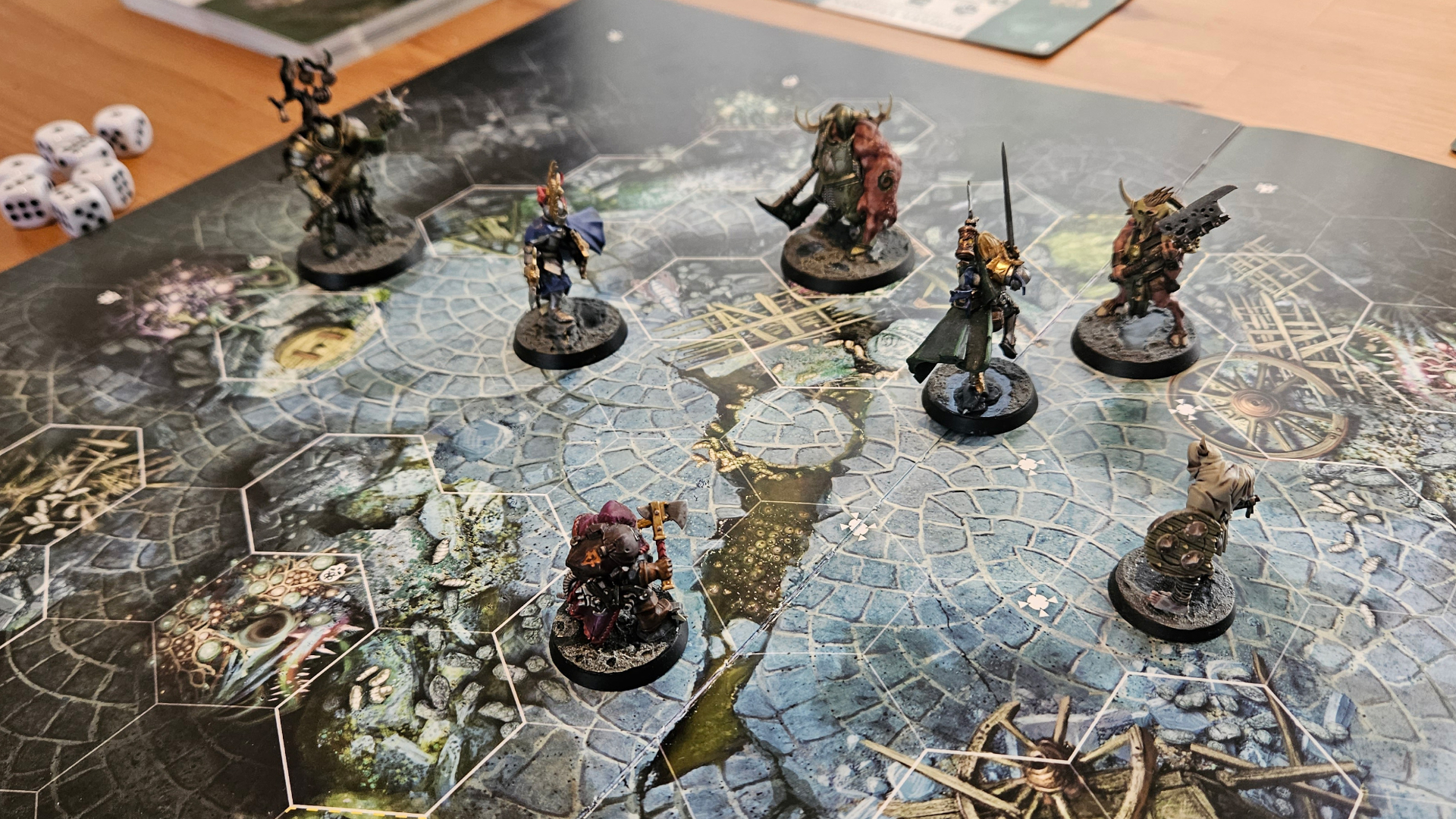 A series of models laid out on the Warhammer Quest: Darkwater board book