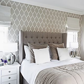 bedroom with grey headboard and wallpaper wall