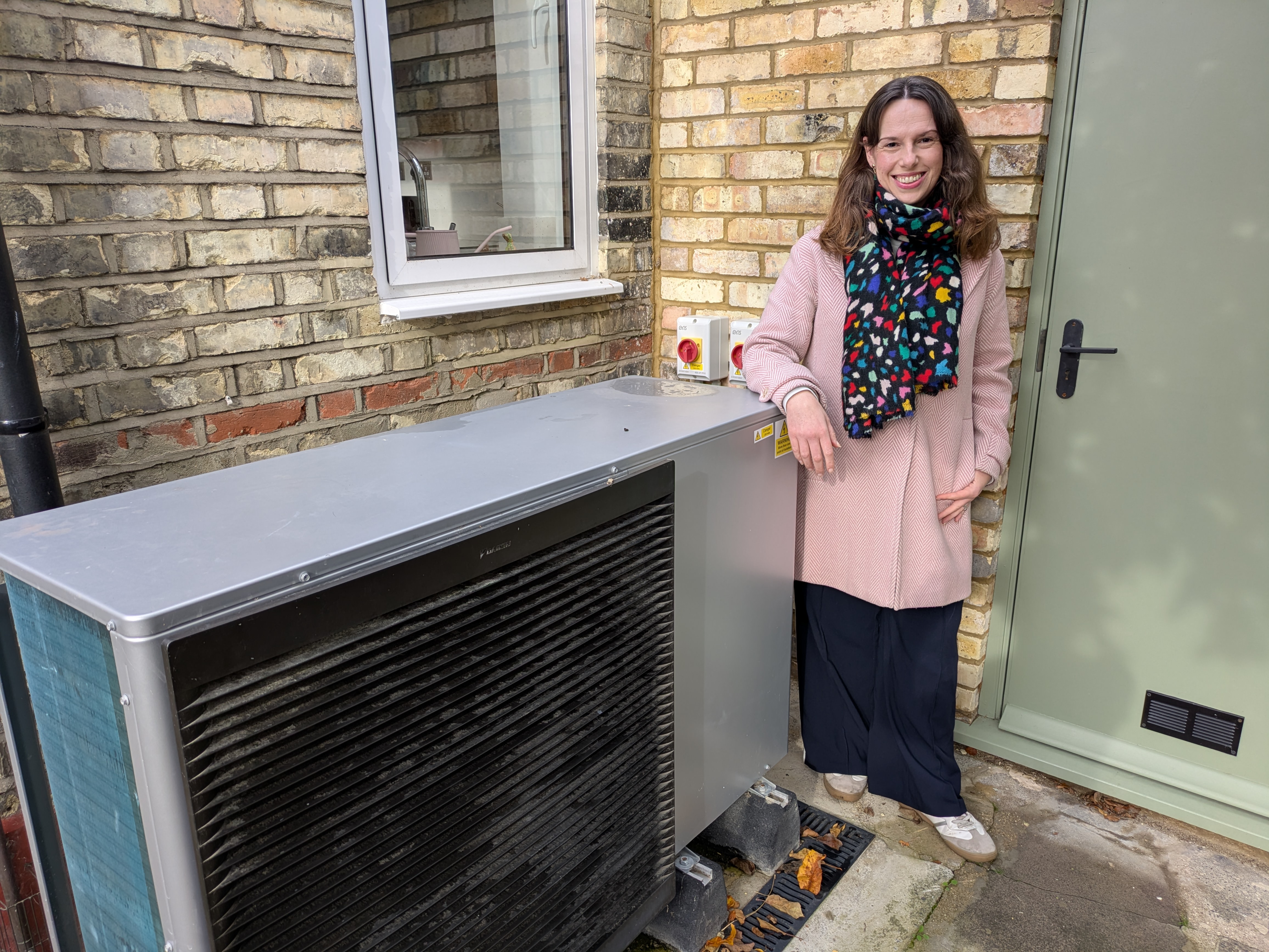 Ruth Emery stands next to her heat pump