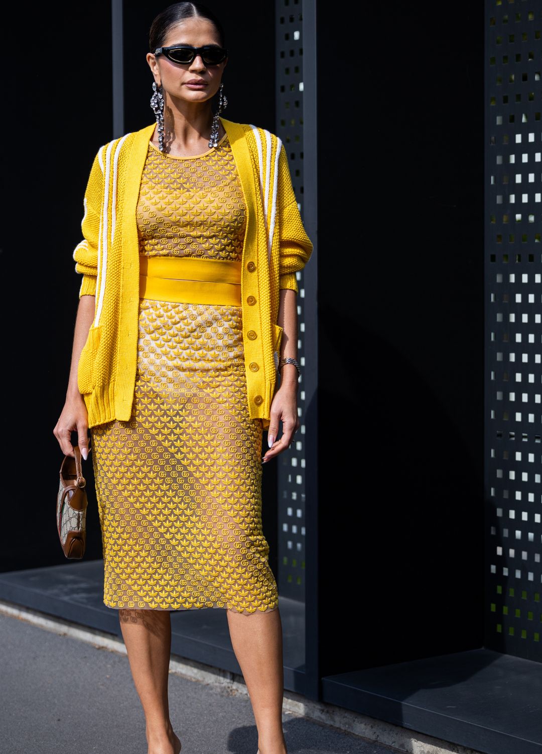 Thassia Naves is seen wearing a black Gucci sunglasses, transparent tulle top and skirt from Gucci x Adidas, a yellow and white print pattern wool cardigan from Gucci x Adidas and a beige monogram Gucci handbag outside the Gucci show during the Milan Fashion Week - Womenswear Spring/Summer 2023 on September 23, 2022 in Milan, Italy