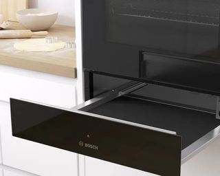 warming drawer in a bosch oven in a white kitchen with wood countertops - Bosch