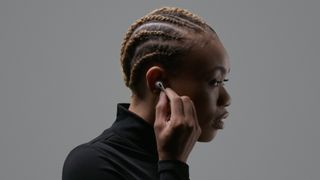 AirPods Pro worn by a woman with a grey wall behind her