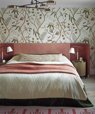 bedroom with patterned wallpaper and bed and sidetables with lamsp and pink throw