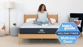 Bear Original Mattress holiday sale image shows a woman with curly dark hair smiling while sitting on top of the mattress
