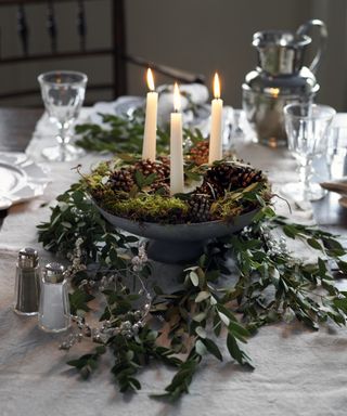Thanksgiving centerpiece ideas with a foilage runner and moss-filled centerpiece bowl with three candles