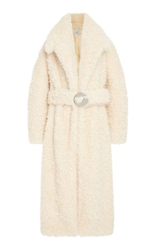 a white Coperni belted faux shearling coat in front of a plain backdrop