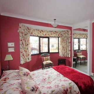red wall with floral printed curtains and mirrored built in wardrobe