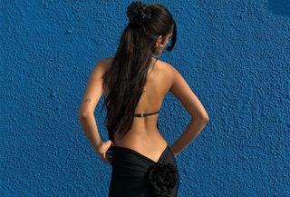 best adhesive bras, close up photo of a woman wearing a black backless dress with a rosette and a strapless adhesive bra