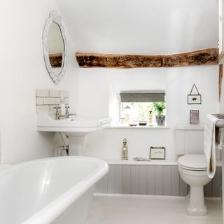 White bathroom with freestanding bath and wooden ceiling beam