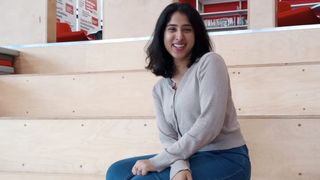 Tom's Guide Sleep Staff Writer Becky George sits on a series of light wooden steps while smiling into the camera