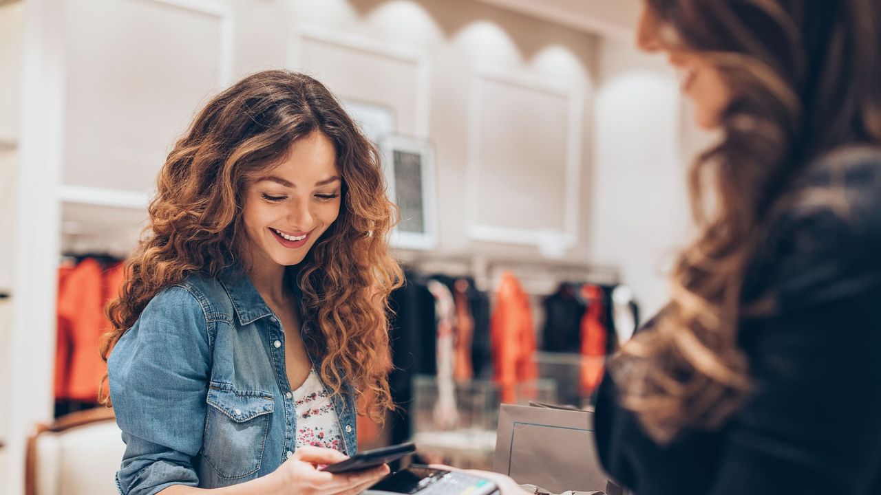 young woman making a contactless payment in a fashion store