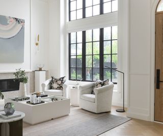 living room with cream walls and furniture and high arched window