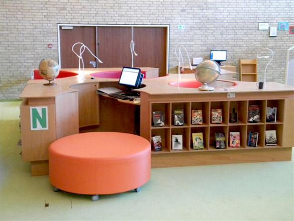 A large open space with central island of children's workstations including computers, globes and cubby holes for books.